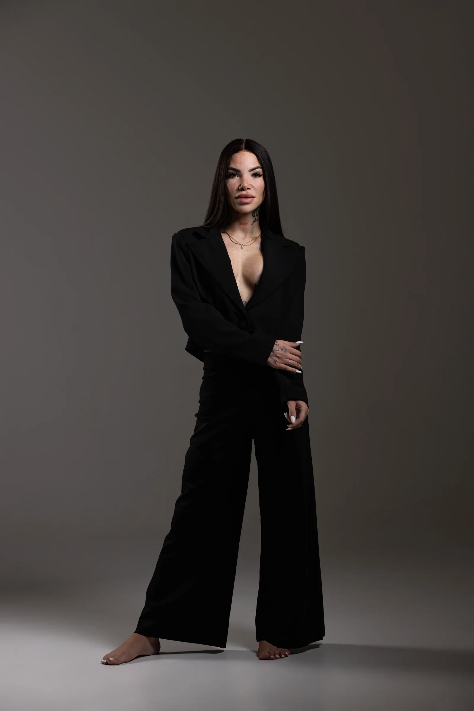 Vitória Guarizo usando terno preto em retrato de corpo inteiro